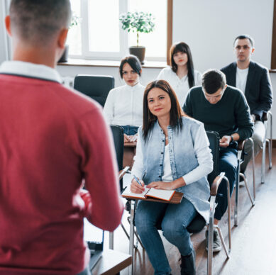In red shirt. Group of people at business conference in modern classroom at daytime.